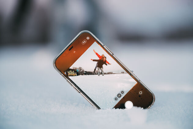 自画像在冬天的乡间 一个男人背着女友 一边玩 一边用放在雪地上的智能手机自拍寒冷自然爱