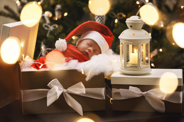 有趣可爱的新生儿戴着圣诞老人的帽子睡在圣诞礼盒里圣诞快乐 新年快乐灯笼迷人梦