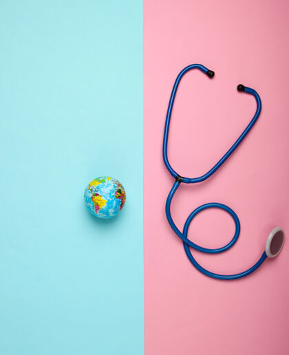 全球全球流行病的问题听诊器和地球仪在粉蓝色墙壁上全球流行顶视图病毒设备医学