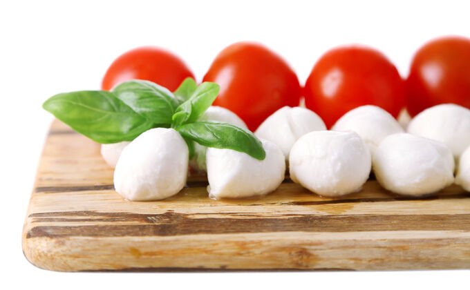 马苏里拉美味的马苏里拉奶酪球 罗勒和红西红柿 放在切菜板上 放在白面包上木材叶新鲜