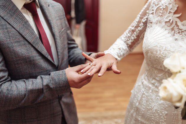 新娘新郎把金戒指戴在新娘的手指上婚礼戒指幸福男性
