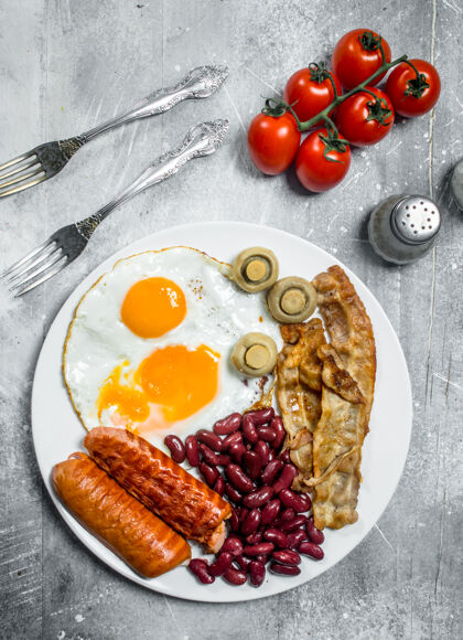 切片英式早餐乡村餐桌上的香肠 培根和豆子煎蛋番茄叉子不健康