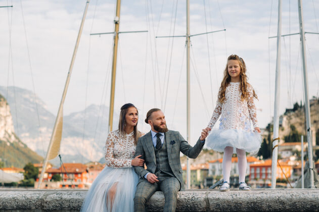 海岸意大利 加尔达湖美丽的家庭在阿尔卑斯山脚下的意大利加尔达湖畔父亲 母亲和女儿在意大利阳光美丽阿尔卑斯山