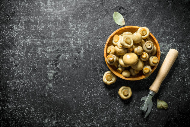 蘑菇木制盘子上的蘑菇罐头 乡村餐桌上有开瓶器有机辛辣美味