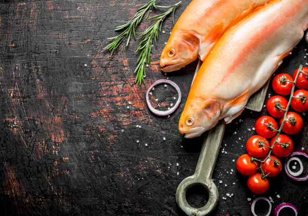 河流生鳟鱼配樱桃番茄 迷迭香和洋葱圈 放在深色的乡村餐桌上鳍鲑鱼动物
