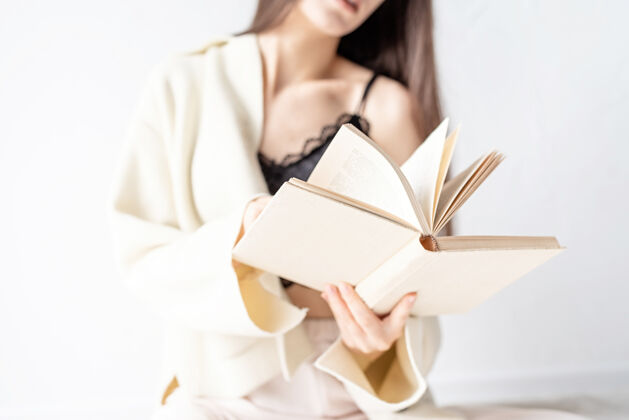 阅读美丽的微笑着的女人穿着舒适的家居服坐在地板上微笑着看书可爱空白房子