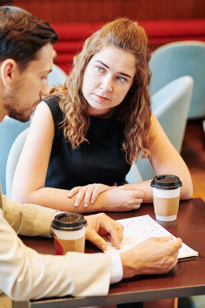 年轻人严肃的年轻女商人在咖啡厅的会议上倾听同事或商业伙伴的想法咖啡馆情侣女性