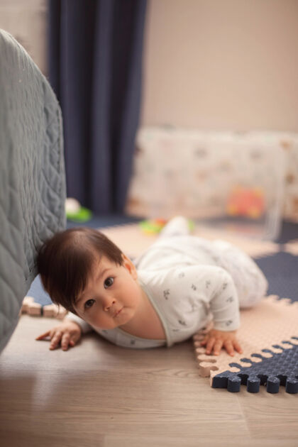 躺着穿着明亮的睡衣 一头黑发的漂亮男婴正在学习爬行 趴在托儿所的地板上卧室床婴儿床