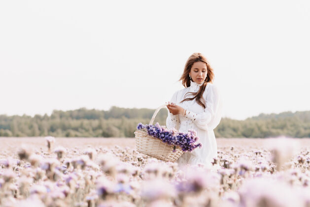 户外夏天 田野里的女孩拿着花篮里的一束鲜花生活方式花美丽