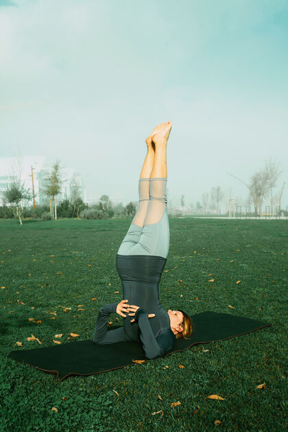 时尚在公园里用瑜伽垫做瑜伽 伸展运动 锻炼的年轻女子天生的瑜伽初学者姿势医疗理念健康锻炼年轻