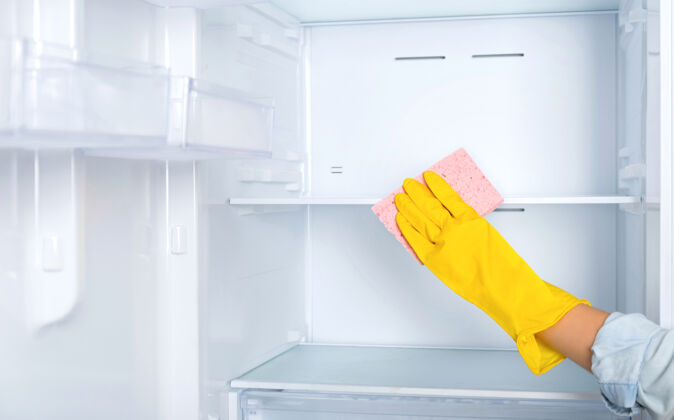 消毒一个戴着黄色橡胶防护手套和粉色海绵的女人用手清洗冰箱货架.清洁服务 家庭主妇 日常事务家务.玻璃更干净洗衣清洁剂保护