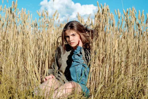 乡村穿礼服的漂亮女孩模特反对田野的背景小麦蓝天空 自由和炎热的夏天的概念女人日落阳光