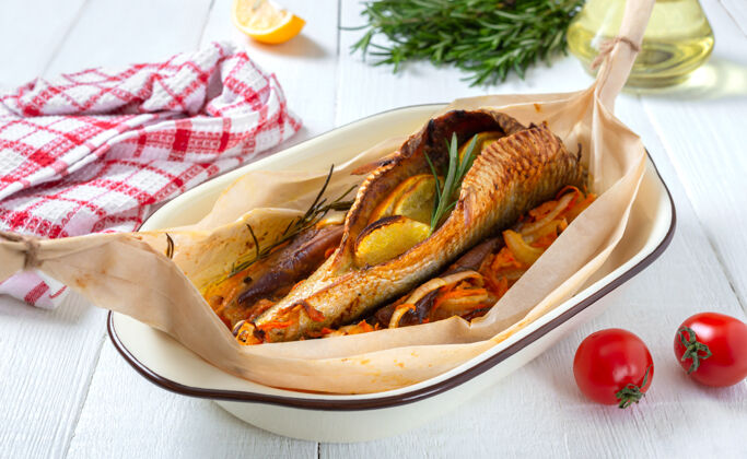 鱼在白色的木头上 用蔬菜 香草和橘子烤成的整条鱼烧烤西红柿香料
