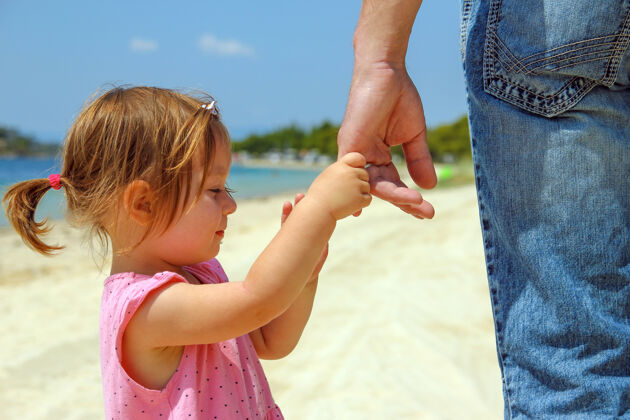 宝贝在海边的海滩上 父母牵着一个小孩的手助手舒适手指