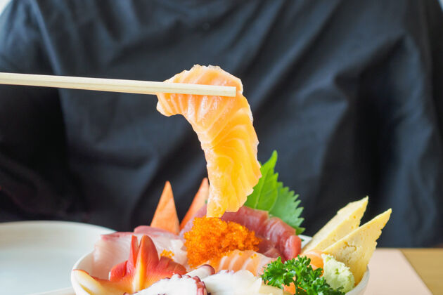 鲑鱼用筷子夹三文鱼片 吃生鱼片饭碗吃日本料理餐桌鱼虾