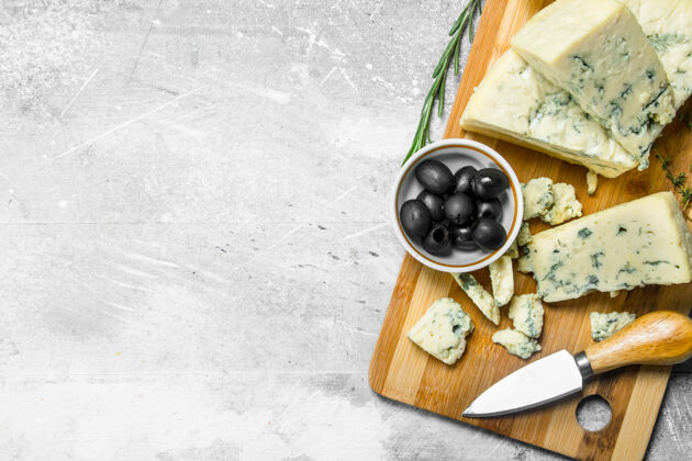 餐桌木头上有橄榄的蓝芝士董事会一张质朴的桌子午餐奶酪杂货店