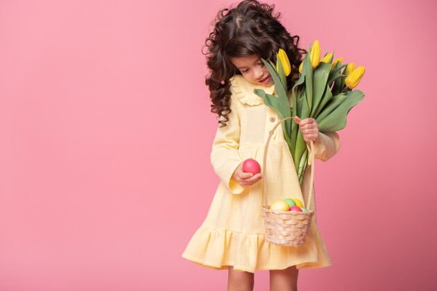 肖像漂亮的小女孩拿着篮子 篮子里放着复活节彩蛋和粉色的郁金香惊喜孩子节日