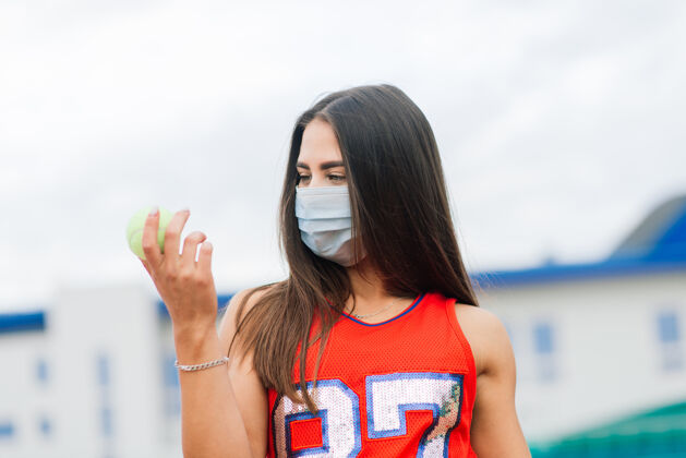 穿着网球运动员的肖像女孩拿着一个球外面的防护面具网球快乐健身