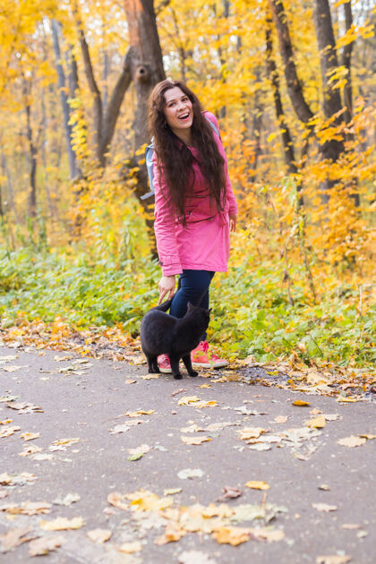 森林女人和黑猫在秋天公园散步美丽爱情公园