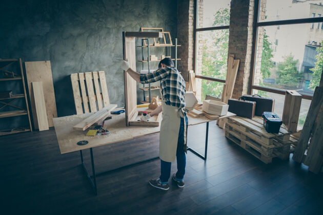 杂工背面全长集中工人手工企业家更新板桌用钻固定家中车库里的木制品人板工匠