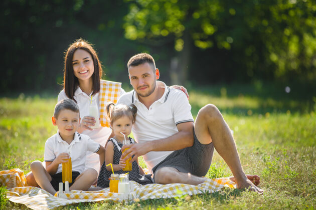 喝酒快乐的家庭野餐父母在户外和孩子们一起吃晚饭成人节日吃饭