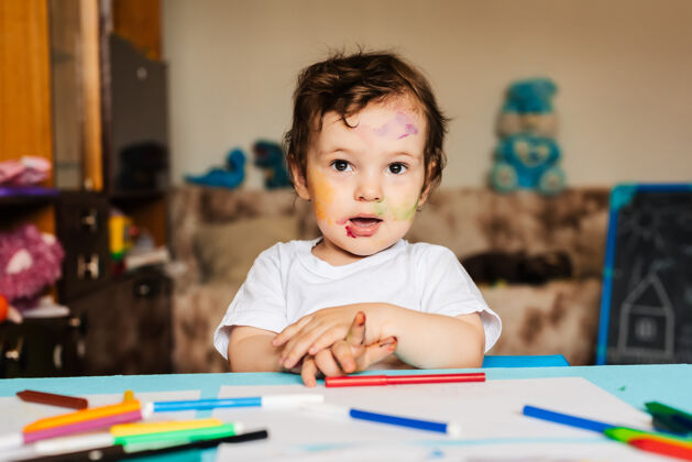 小快乐的小男孩用彩色记号笔在一张纸上画画教育学习桌子