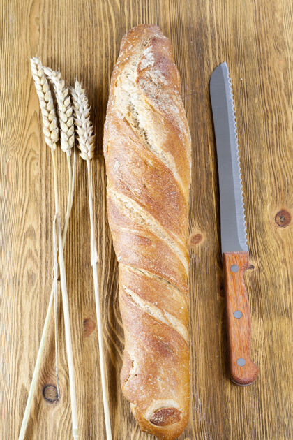 自然一个新鲜的浅色面包与一个美味的脆 在厨房特写与刀和小穗的树桩刀种子健康