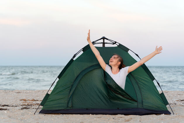 睡眠女孩在早晨伸展四肢帐篷.露营由海上旅行 徒步旅行 露营旅行旅游海滩