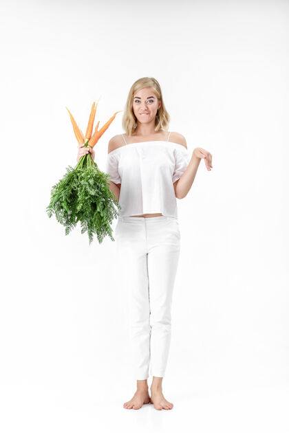 人美丽的金发女郎展示着兔子 手里拿着一根新鲜的红萝卜 红萝卜上有绿叶背景.健康还有节食橙色肖像生活方式
