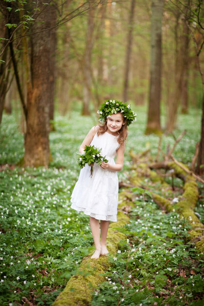 女性穿着白裙子的漂亮小女孩在春天散步伍德肖像画美丽的小女孩头上戴着春花的花环小径家庭温柔
