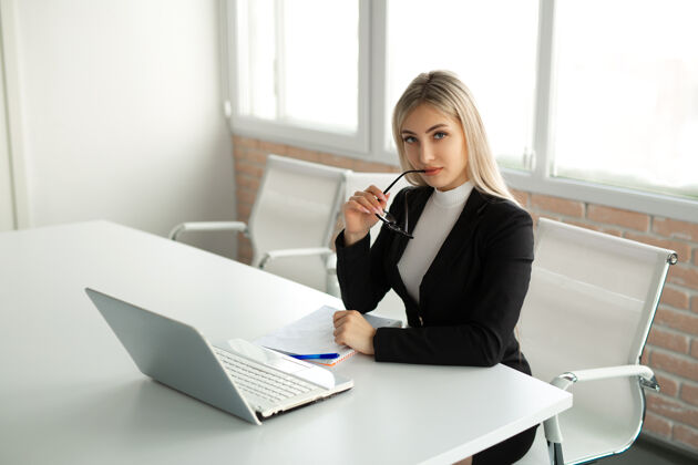 日语漂亮的年轻女子穿着西装在办公室的桌边拿着笔记本电脑笔记本秘书经理