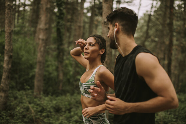 运动一对年轻的健身情侣在夏天的森林小径上跑步休闲能量人