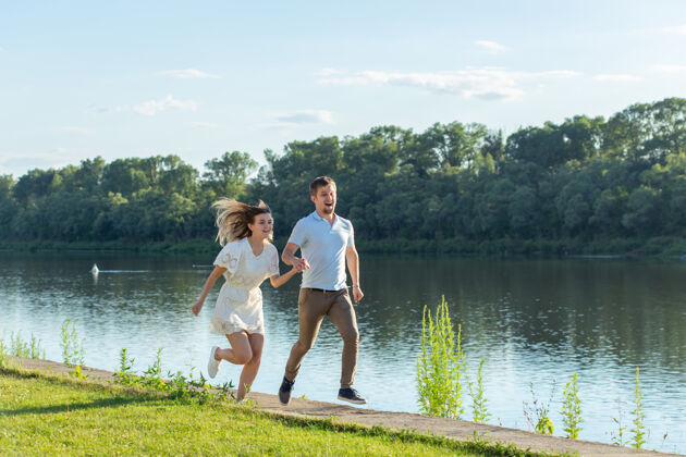 情侣爱情和关系概念-快乐的男人和女人在湖边的公园里奔跑爱河流水