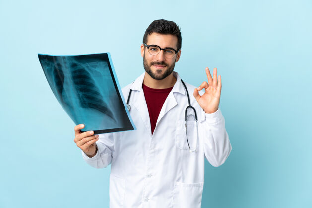 人专业的创伤科医生拿着蓝色的X光片 用手指显示ok的信号专业护理创伤