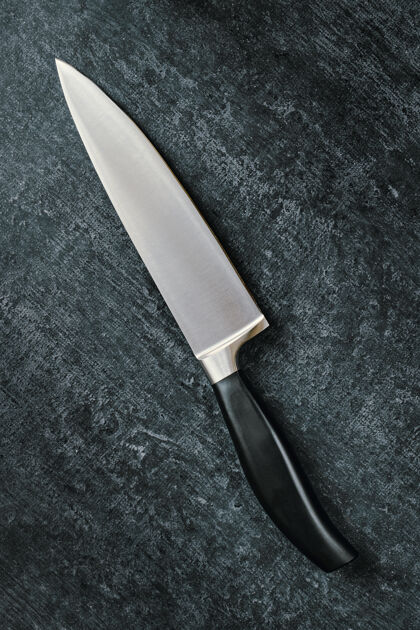 餐具厨师的菜刀斜放在黑暗的表面上刀片深色背景对角线