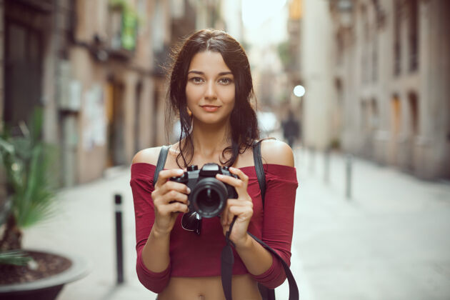 巴塞罗那迷人的旅游女摄影师用数码单反相机看着相机在户外的城市街道休闲专业女孩