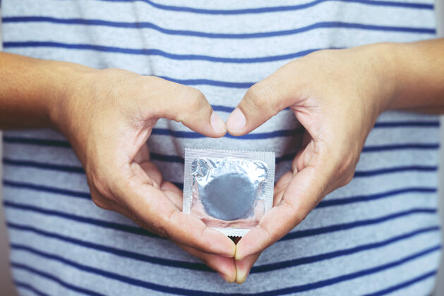 年轻安全套随时可在女性手中使用 给予安全套安全的性观念 在床上预防感染和避孕 控制出生率或安全预防世界艾滋病日包装护理医疗保健
