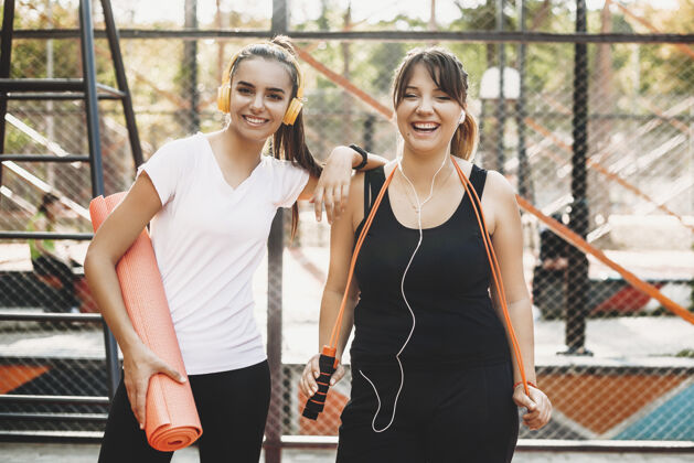 训练年轻的女人在早上和她的女朋友一起运动时大笑一起健身肌肉
