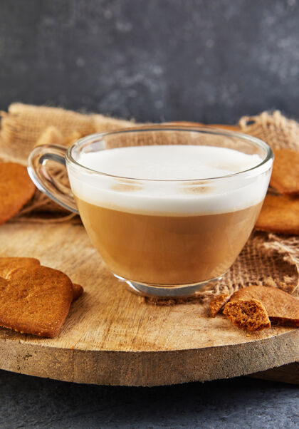 早晨心形姜饼饼干和一杯卡布奇诺咖啡放在木板上咖啡馆小吃咖啡