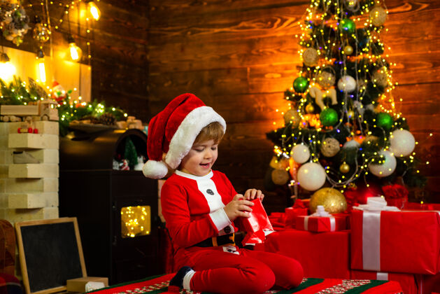 可爱圣诞节孩子们快乐小男孩穿着圣诞老人的衣服 玩着圣诞礼物包围着的圣诞礼盒丝带季节举行