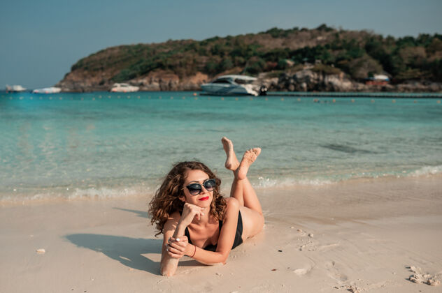 阳光蓝海海滩上一个卷曲的黑衣女孩女人放松海滩