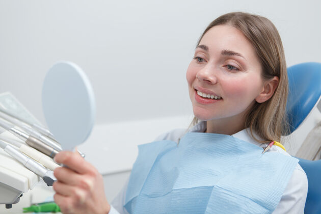 镜子美丽的女人检查完牙齿后在镜子里检查她健康的白牙治疗卫生保健