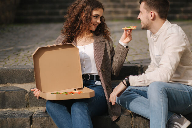 咖啡坐在室外楼梯上吃比萨饼的年轻夫妇情侣生活方式检疫