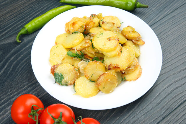 烧烤木桌上的一个盘子里放着香草和蔬菜的炒土豆农业美味烹饪