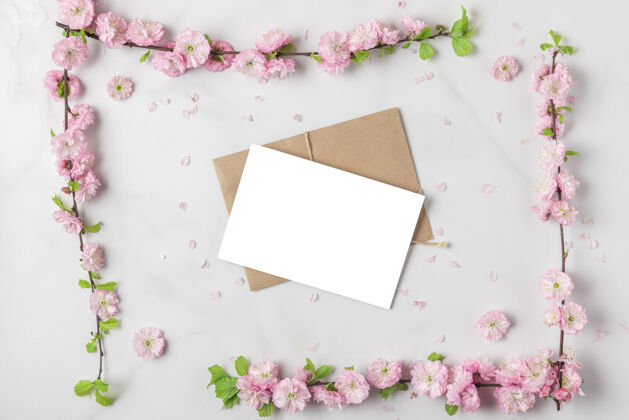 花白色大理石上春天粉红色樱花枝制成的相框贺卡背景.平坦躺着视图.假日或婚礼版面复制空间花头顶樱花