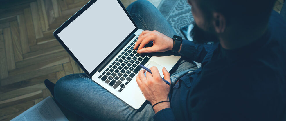 现代上图是一位高加索男子拿着笔记本电脑在家工作 地板上有空闲空间计算机肖像人