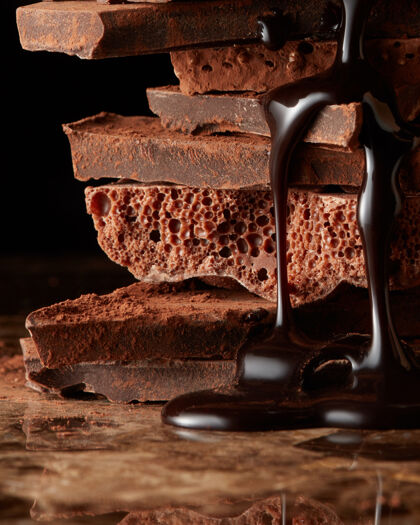 块融化的巧克力倒在一堆黑巧克力片上糖浆甜点块