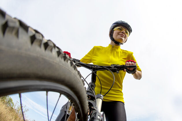 自行车在晴朗的天空中骑着自行车的穿着黄色衣服的漂亮女人背景.运动以及娱乐.自然还有伙计道路户外自行车手