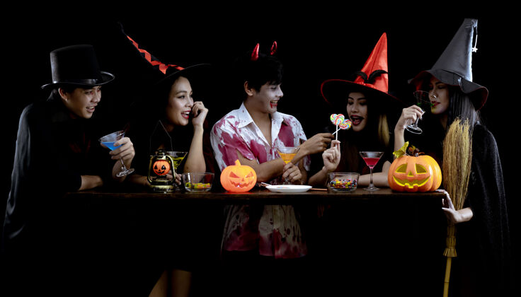 饮料一群穿着服装的亚洲年轻人在黑墙上庆祝万圣节派对 万圣节时尚节的概念…服装鬼魂 一群泰国年轻人的邪恶血灯邪恶