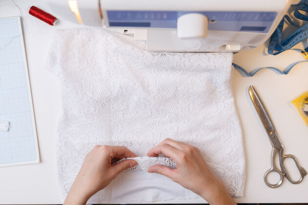 细节女裁缝在缝纫机上准备缝纫用的布料设备针墙壁